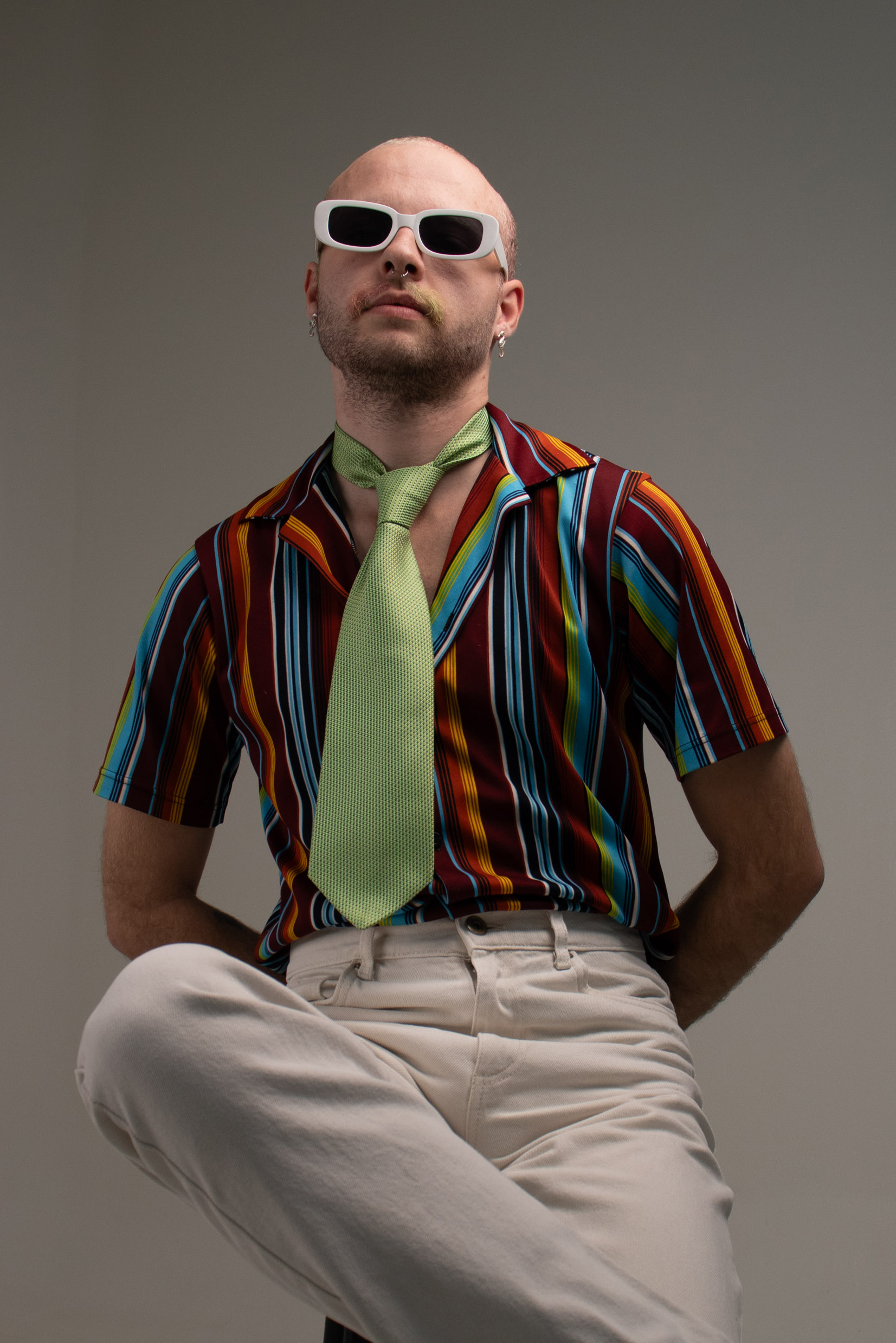 A young man with a multicolour mustache wearing bright clothing